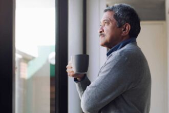 Shot of a senior man drinking coffee and looking thoughtfully out of a window