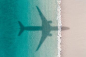 Aerial shot showing an aircraft shadow flying over an idyllic beach