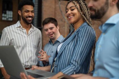 Cheerful young businesspeople with laptop working in office