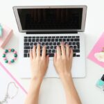 A closeup of a woman typing on a laptop computer.
