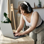 A woman working from home on her laptop reading a review on Apple work from home jobs