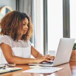A woman searching for jobs on a laptop in her home office.
