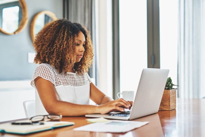 A woman searching for jobs on a laptop in her home office.