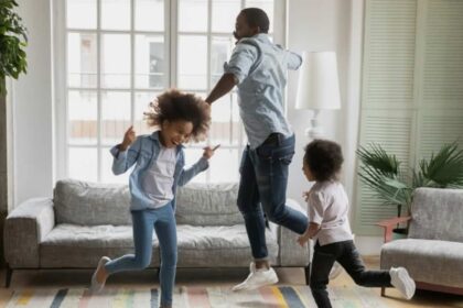 Black father and two young daughters dancing at home