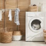 A laundry room in a remote worker's home, with a washing machine, drying rack, and laundry baskets.