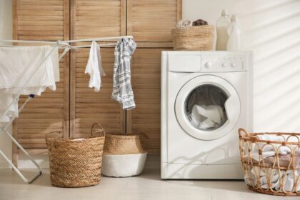 A laundry room in a remote worker's home, with a washing machine, drying rack, and laundry baskets.