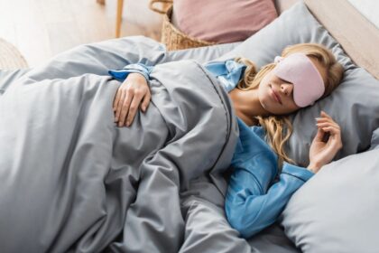 A woman sleeping in bed and wearing a sleep mask.