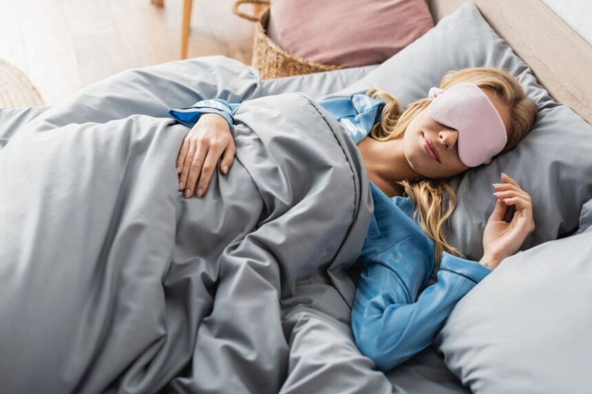 A woman sleeping in bed and wearing a sleep mask.