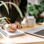 A woman working from home at a desk, surrounded by plants.
