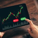 Investor looking at stock graph on a tablet with their finger hovering over the Buy button