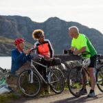 Friends at the bay near the village of Diabaig on the side of Loch Torridon in Wester Ross, Scotland. They are taking a break from their bike ride to relax and chat. They are laughing together.