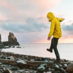Man hanging in the balance over a log at seaside in Scotland