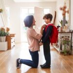 Mother At Home Getting Son Wearing Uniform Ready For First Day Of School