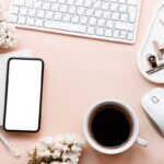Overhead image of wedding flowers and accessories on a remote worker's desk.