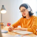 Woman working at home and writing in a notebook at a desk.