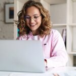 Woman working in her home office, sitting at a desk, using a laptop.