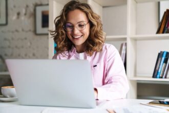 Woman working in her home office, sitting at a desk, using a laptop.