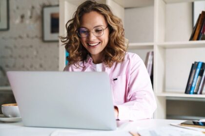 Woman working in her home office, sitting at a desk, using a laptop.