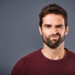Young Caucasian man making doubtful face at camera