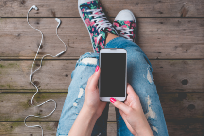 Young woman in ripped jeans and high top tennis shoes using a mobile phone