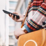 A woman using a smartphone while walking on the street in the city.