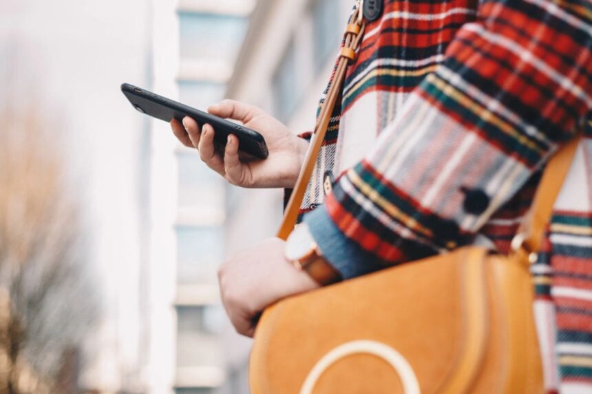 A woman using a smartphone while walking on the street in the city.