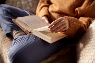 A woman sitting on a couch, reading a book.