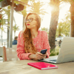 Young girl working on her laptop near the beach