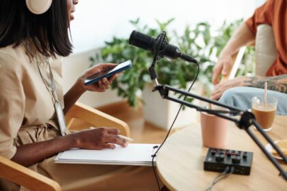 A woman recording a podcast, using a microphone and writing notes on a notepad.